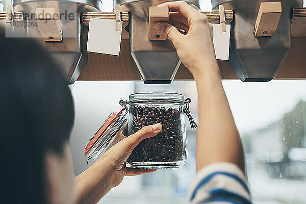 Frau füllt Einmachglas mit Kidneybohnen im Supermarkt