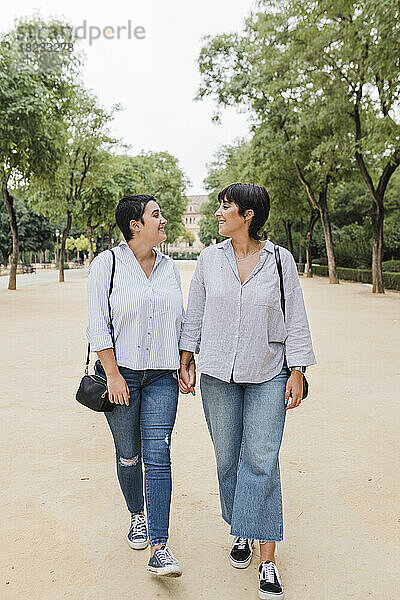 Lesbische Freundinnen gehen Händchen haltend im Park spazieren