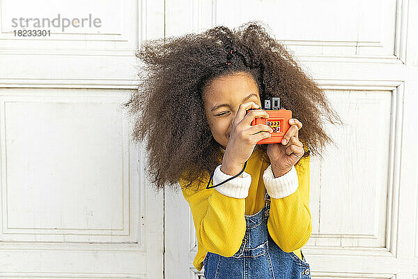 Mädchen fotografiert mit Spielzeugkamera in der Nähe der Tür