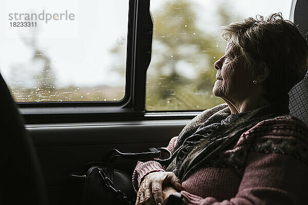 Nachdenkliche ältere Frau schaut durch das Autofenster