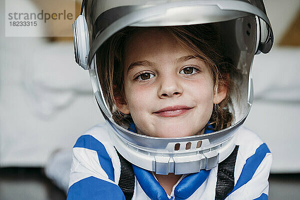 Lächelndes Mädchen im Weltraumkostüm und Helm zu Hause