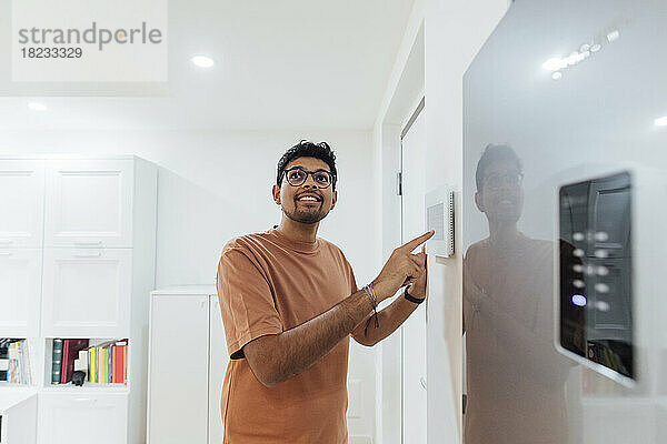 Junger Mann nutzt Smart-Home-Gerät an der Wand