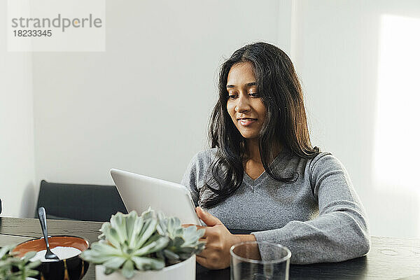 Lächelnde junge Frau  die zu Hause mit einem Tablet-PC lernt