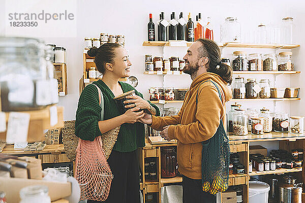Lächelndes Paar mit Netzbeuteln und Glas im Supermarkt