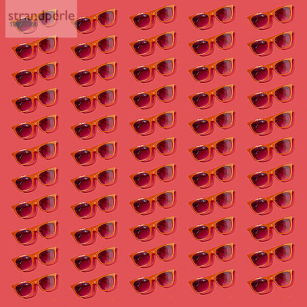 Muster altmodischer Sonnenbrillen flach auf rotem Hintergrund gelegt