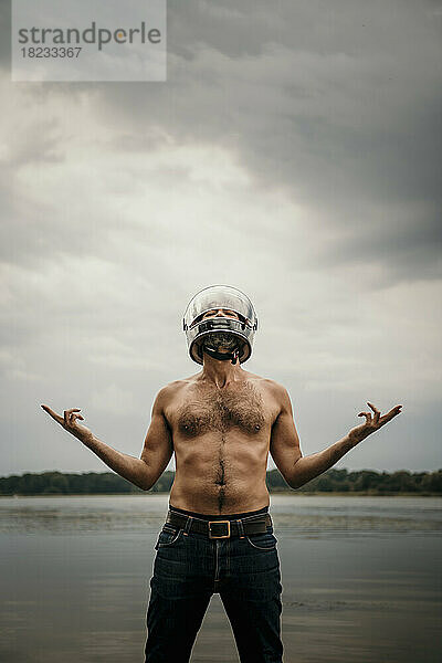 Reifer Mann mit Helm gestikuliert vor dem See