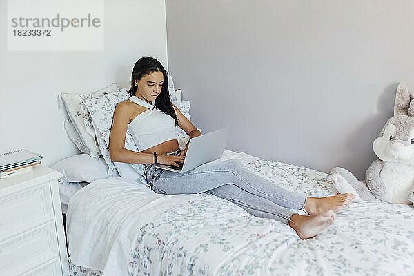 Girl using laptop studying in bedroom at home