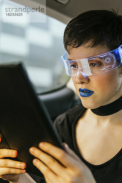 Frau mit Smart-Brille und Tablet-Computer im Auto