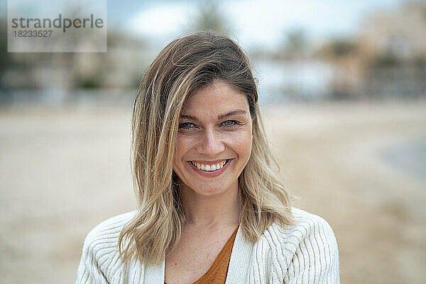 Lächelnde schöne junge blonde Frau am Strand  die das Wochenende genießt