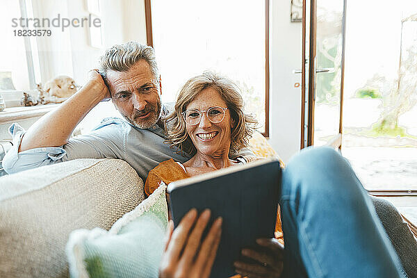 Älteres Paar sitzt mit Tablet-PC auf dem Sofa im Wohnzimmer