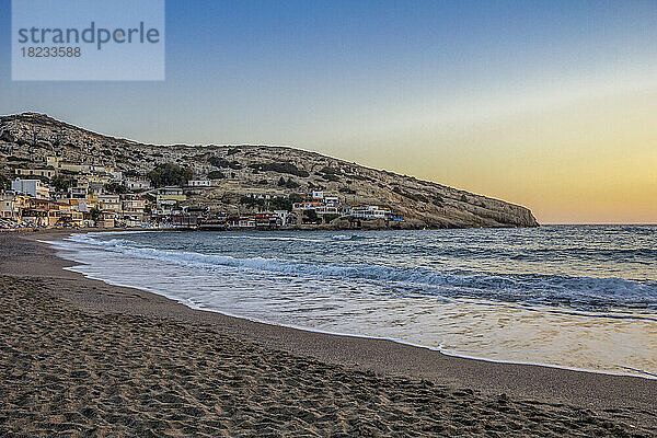 Griechenland  Kreta  Matala  Matala Beach in der Abenddämmerung mit Dorf im Hintergrund