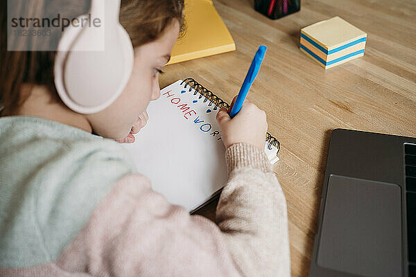 Mädchen schreibt zu Hause auf Notizbuch