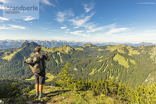 Germany  Bavaria  Male hiker admiring surrounding landscape from summit of Hirschberg mountain