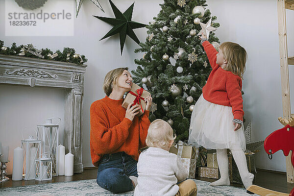 Mutter und Kinder sitzen zu Hause am Weihnachtsbaum
