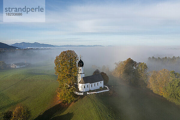 Deutschland  Bayern  Bad Heilbrunn  Luftaufnahme der Kirche Mariä Heimsuchung im nebligen Herbstmorgen