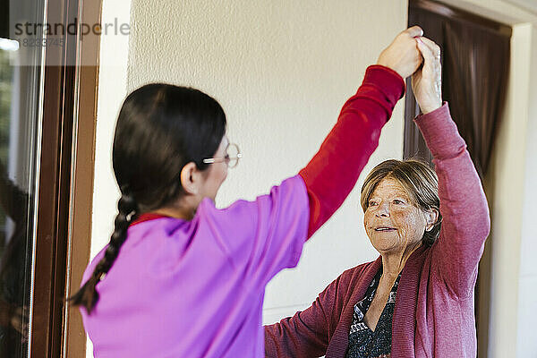 Junge Pflegekraft hilft Seniorin beim Training zu Hause