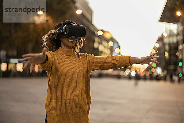 Frau mit Virtual-Reality-Simulator gestikuliert auf Fußweg