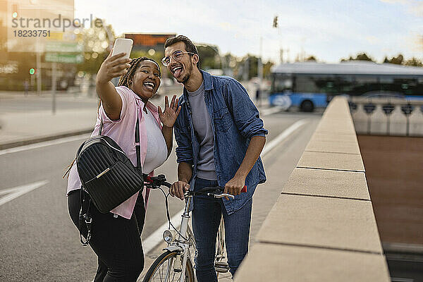 Glücklicher junger Mann und Frau  die am Fußweg ein Selfie mit dem Mobiltelefon machen