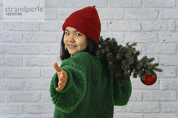 Smiling girl gesturing with Christmas tree