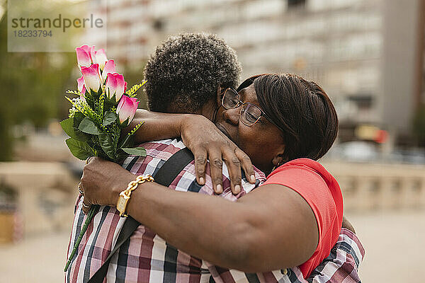 Frau mit Blumenstrauß umarmt Mann