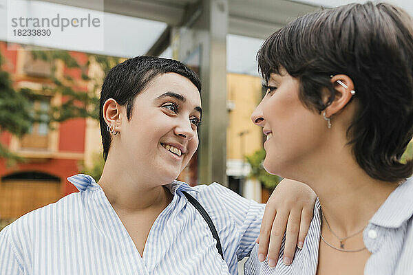 Lächelnde Frau mit der Hand auf der Schulter ihrer lesbischen Freundin