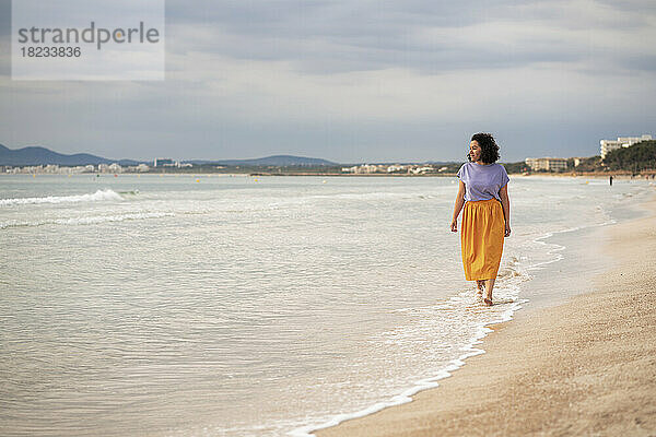 Nachdenkliche Frau  die am Ufer des Strandes spaziert