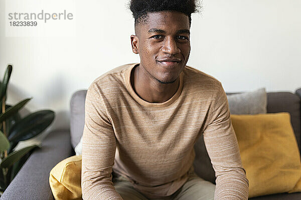 Smiling young man sitting on sofa at home
