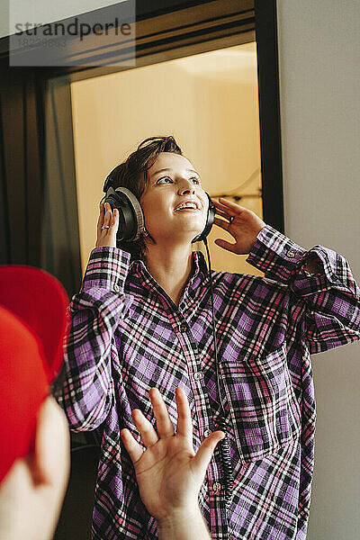 Sänger trägt Kopfhörer vor Kollege im Studio