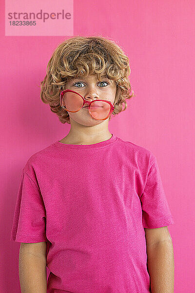 Junge mit farbiger Sonnenbrille vor rosa Hintergrund