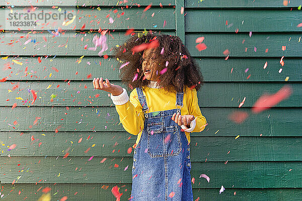 Girl playing with confetti in front of wall
