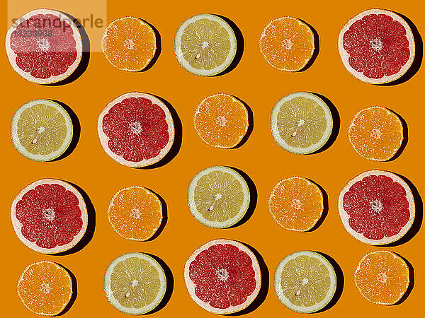 Muster aus halbierten Zitronen  Grapefruits und Mandarinen flach auf orangefarbenem Hintergrund