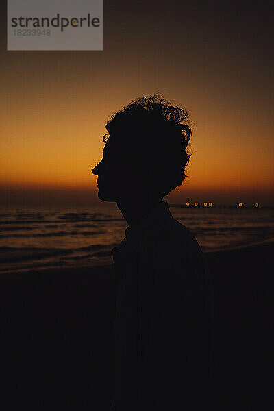 Silhouette einer Frau  die den Sonnenuntergang am Strand genießt