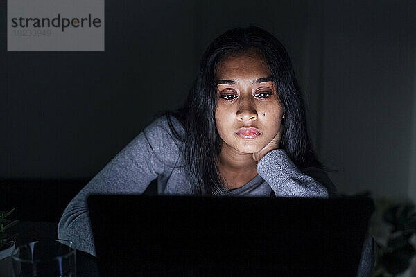 Young woman looking at laptop at home