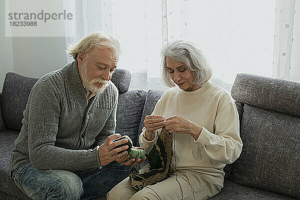 Älteres Paar sitzt auf der Couch und strickt