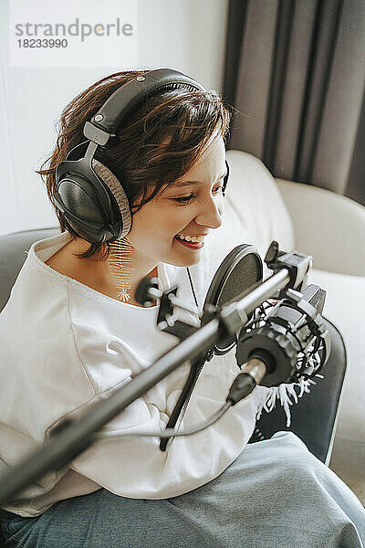 Glücklicher Musiker  der Podcast über das Mikrofon im Studio aufnimmt