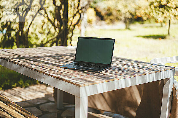 Laptop auf Tisch im Garten