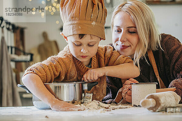 Lächelnde Frau mit Sohn bereitet zu Hause Kekse zu