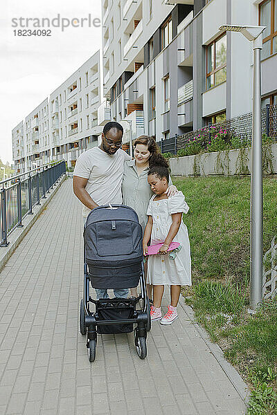 Familie mit Kinderwagen steht am Fußweg