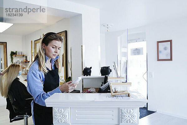 Friseur benutzt Telefon an der Rezeption im Salon