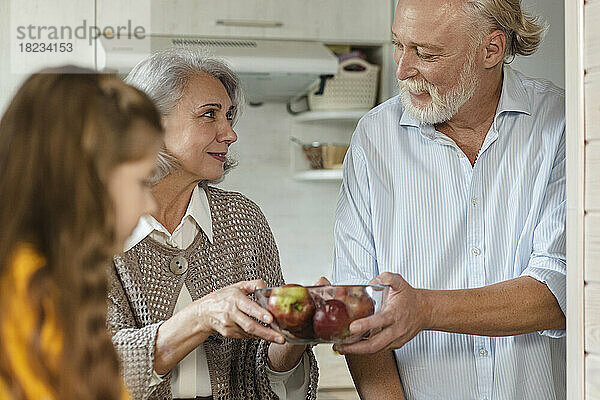 Großeltern halten Schüssel mit frischen Äpfeln in der Küche