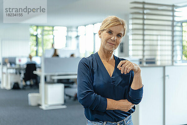 Lächelnde Geschäftsfrau mit blonden Haaren am Arbeitsplatz