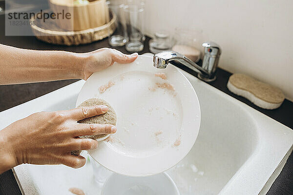 Woman washing dishes with salt in the kitchen