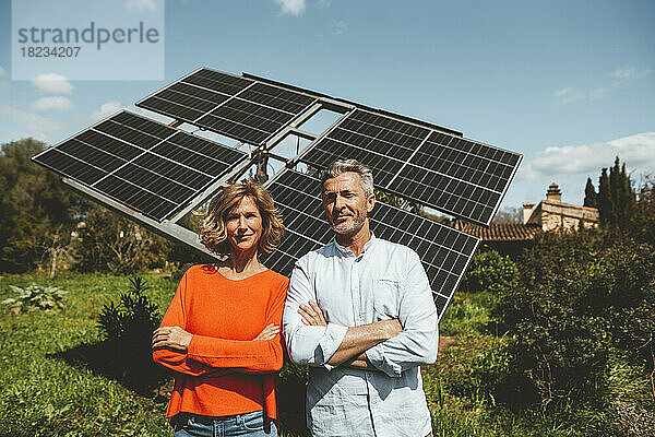 Lächelndes älteres Paar vor Sonnenkollektoren an einem sonnigen Tag