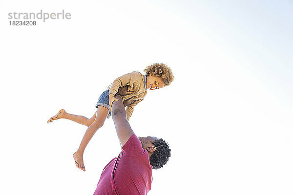 Glücklicher Vater  der an einem sonnigen Tag mit seiner Tochter unter klarem Himmel spielt