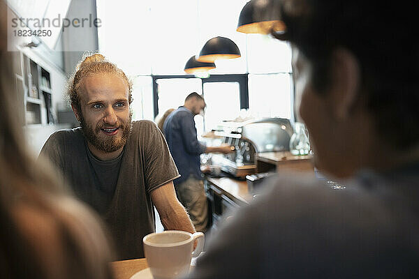 Lächelnder Barista im Gespräch mit Kunden im Café