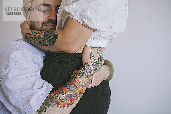 Hipster-Mann mit Tattoo an der Hand umarmt seine Freundin