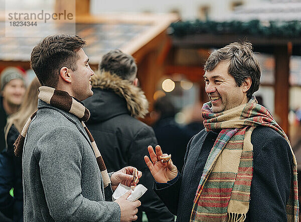 Glücklicher Vater spricht mit seinem Sohn  der auf dem Weihnachtsmarkt steht