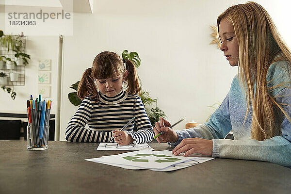 Mädchen mit Schwester zeichnet zu Hause auf Papier