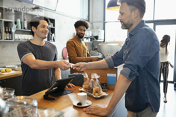 Kunde zahlt mit Kreditkarte am Schalter im Café