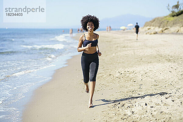 Glückliche junge Frau  die am Strand läuft